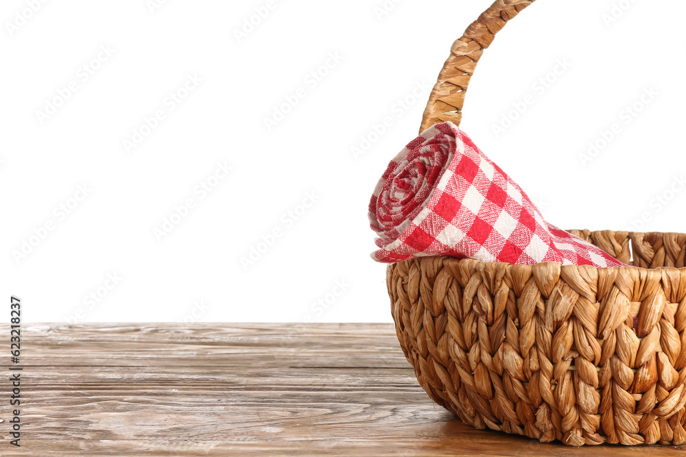 Wicker basket with rolled napkin on wooden table against white background