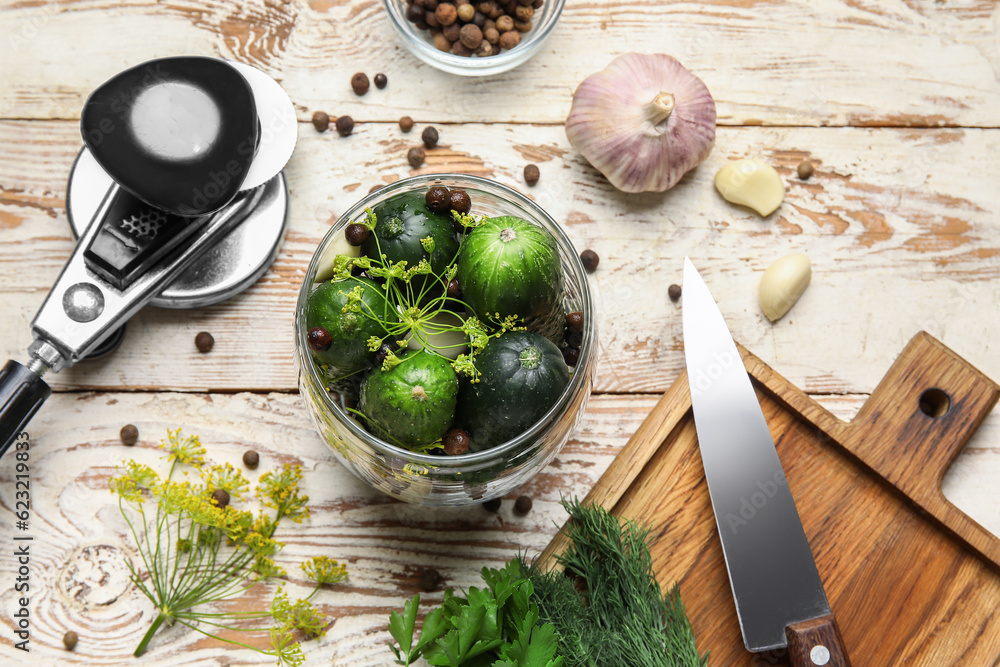 Jar with fresh cucumbers for preservation on light wooden background