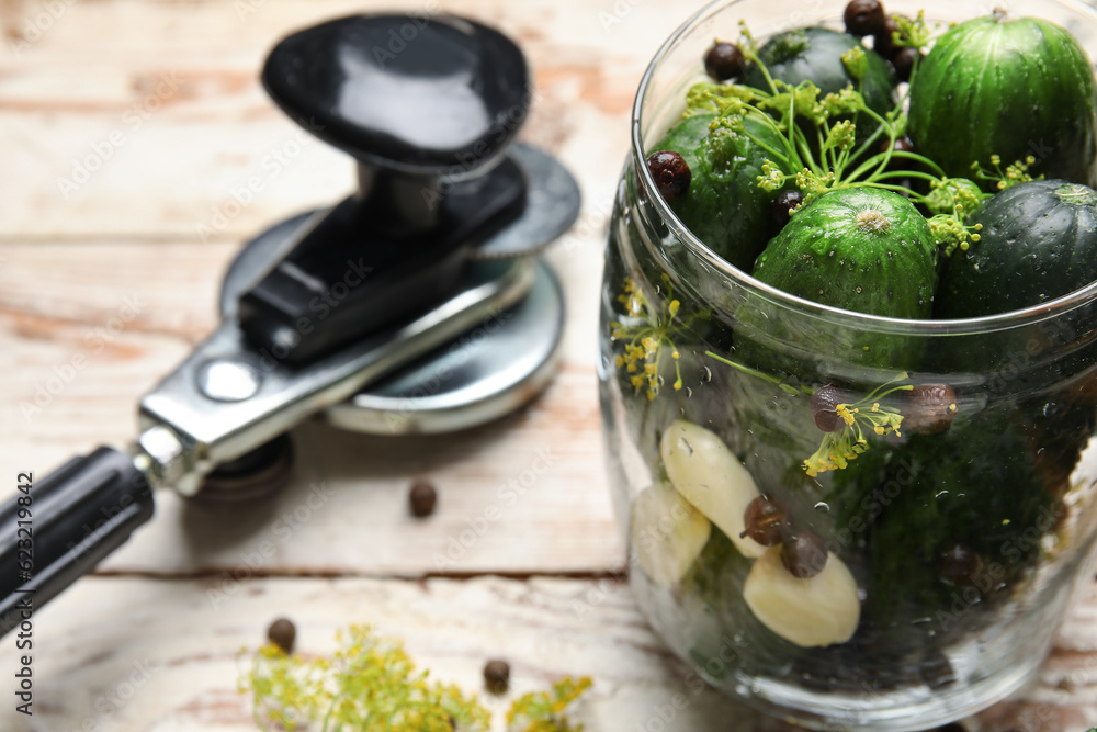 Jar with fresh cucumbers for preservation on light wooden background