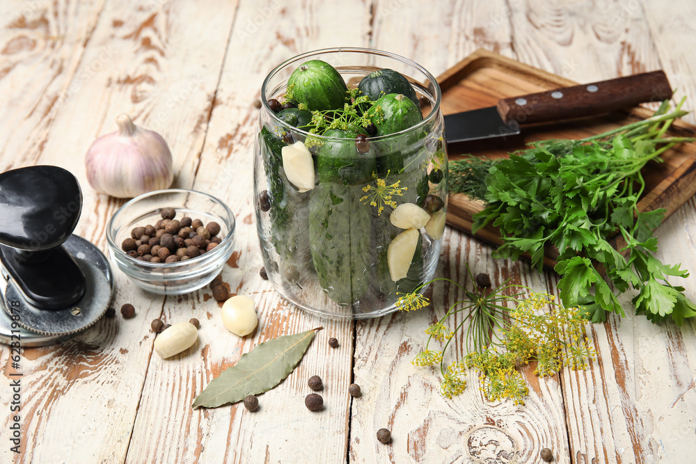 Jar with fresh cucumbers for preservation on light wooden background