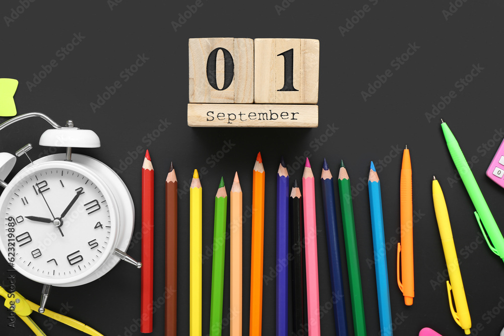 Alarm clock, different stationery and calendar with date SEPTEMBER 1 on black chalkboard