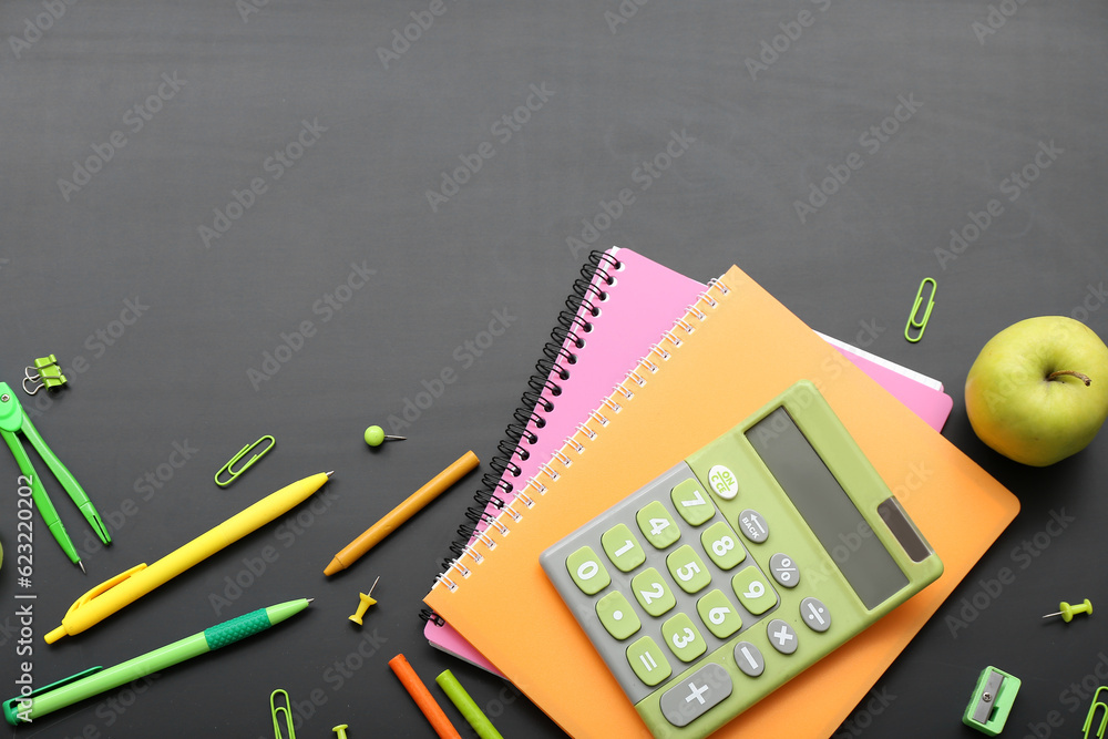 Calculator with fresh apple and different stationery on black chalkboard