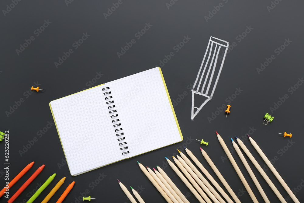 Blank notebook with stationery and drawing on black chalkboard