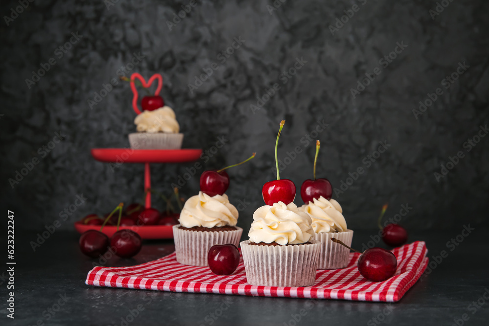 Tasty cherry cupcakes on black background