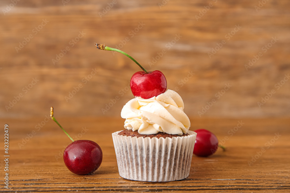 Tasty cherry cupcake on wooden background