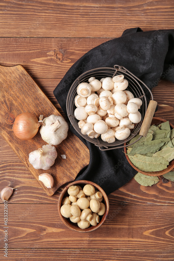 Canned and fresh mushrooms with ingredients for preservation on wooden background