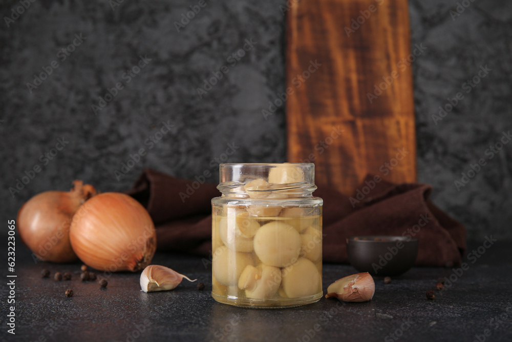 Jar with canned mushrooms on black background