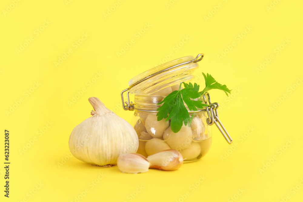 Jar with canned mushrooms on yellow background