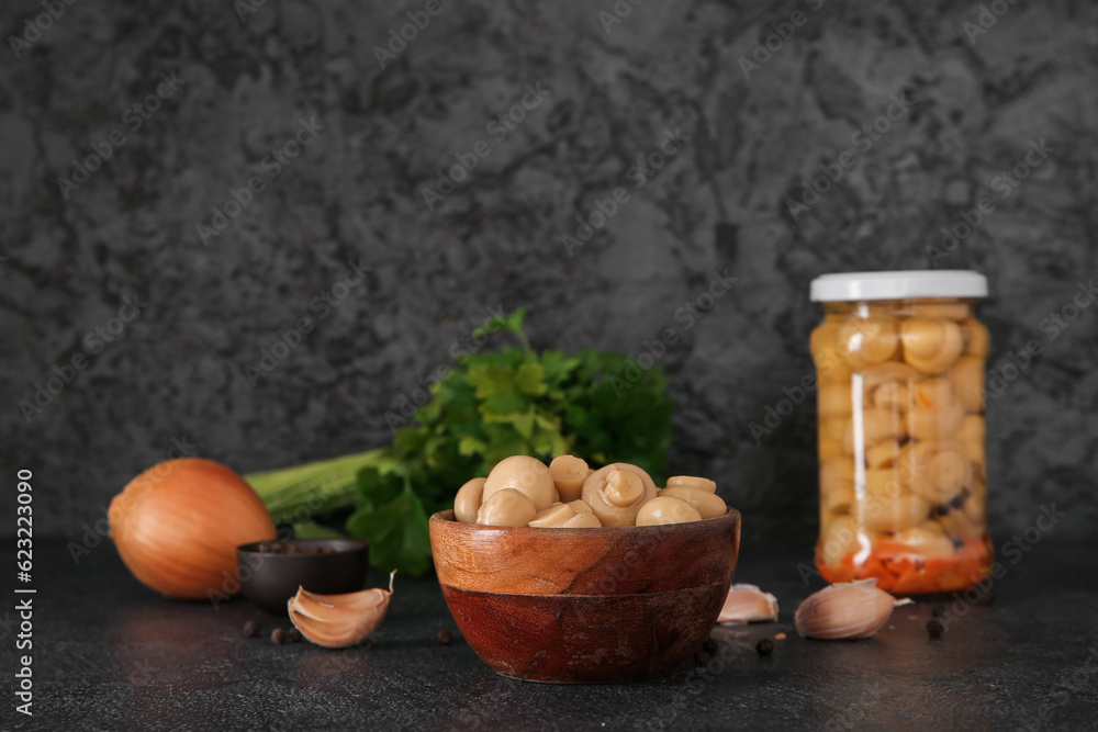 Bowl with canned mushrooms on black background