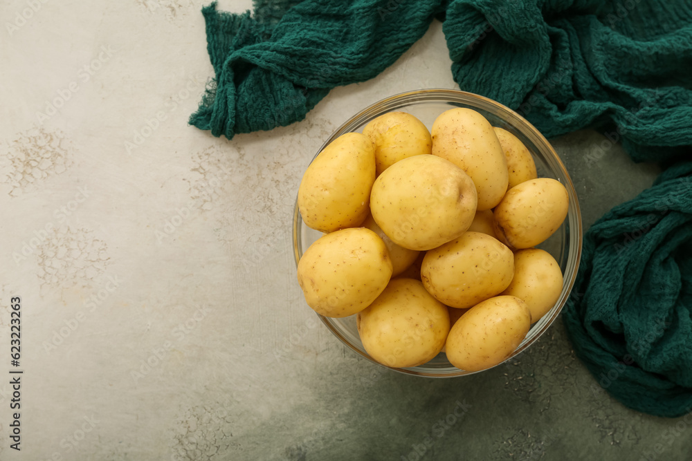 Glass bowl with raw potatoes on white background