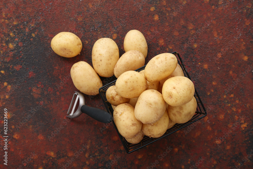 Basket with raw potatoes on dark background