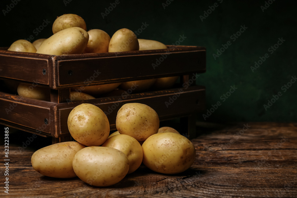 Box with raw potatoes on wooden table