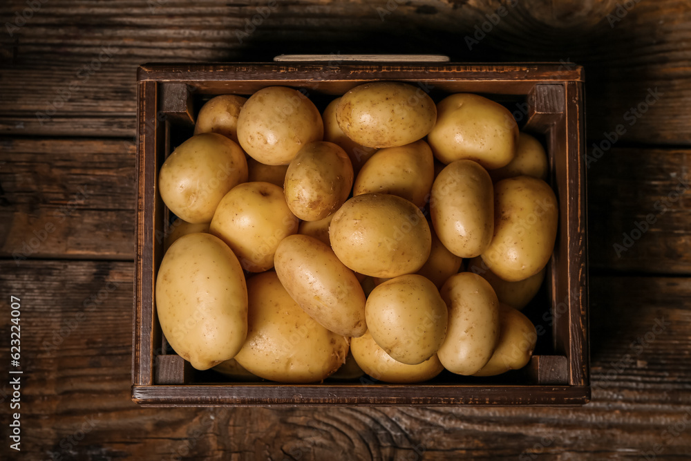 Box with raw potatoes on wooden table