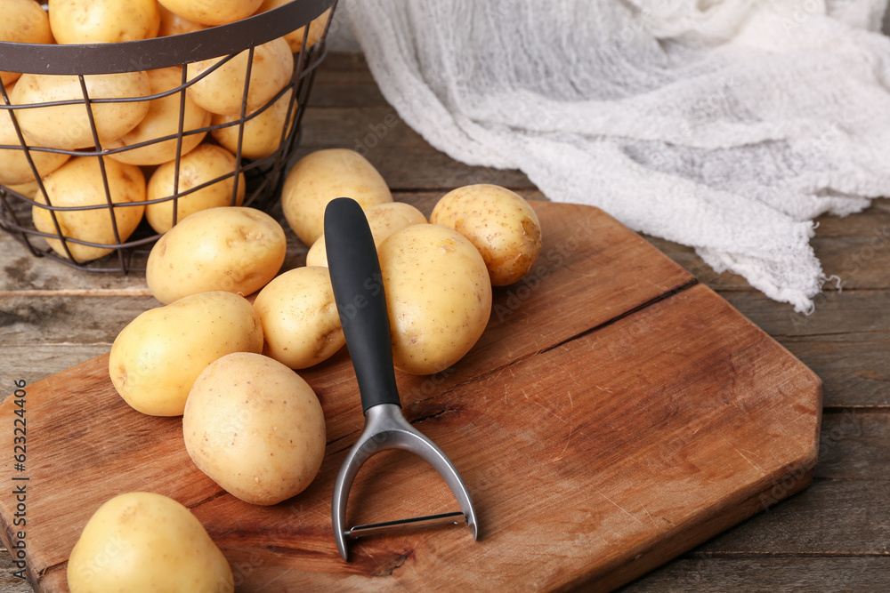 Board and basket with raw potatoes on wooden table