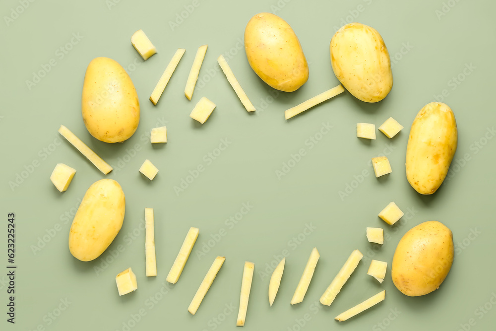 Frame made of whole and cut potatoes on green background