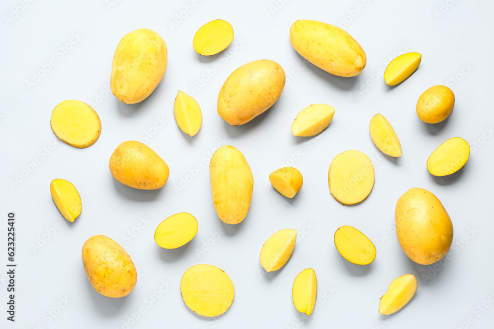 Whole and cut potatoes on blue background