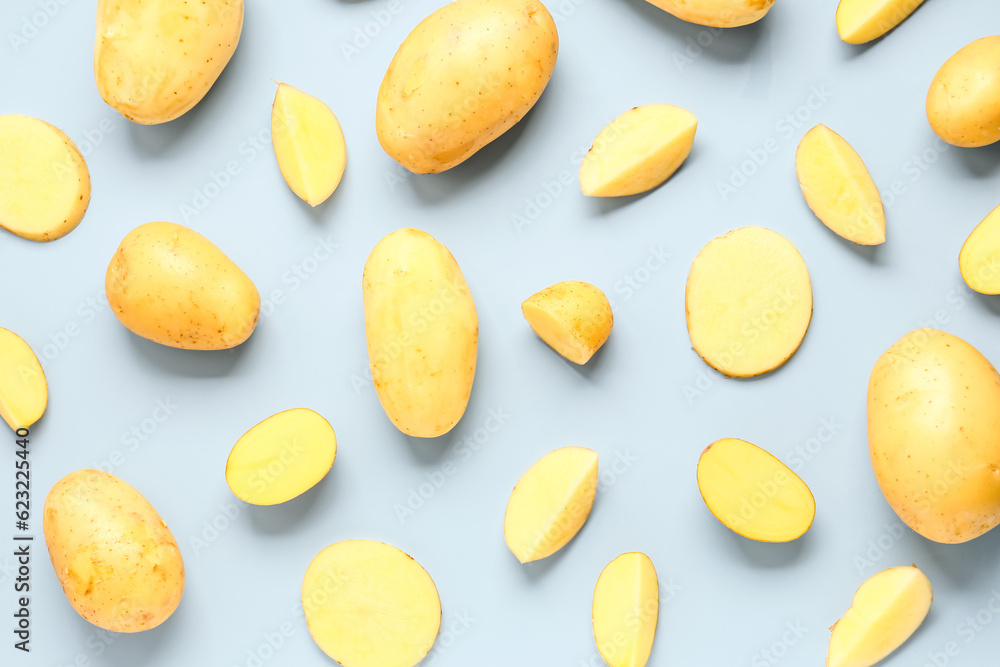 Whole and cut potatoes on blue background