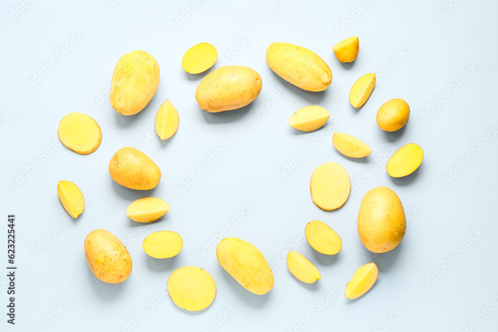 Frame made of raw potatoes on blue background