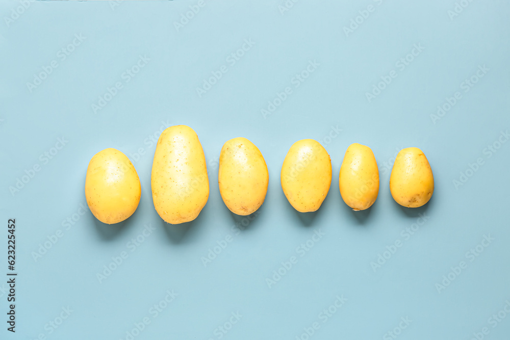 Raw potatoes on blue background