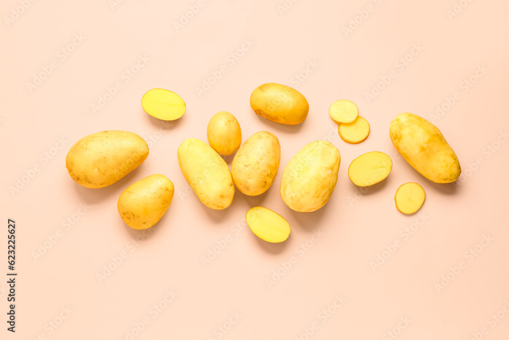 Cut and whole raw potatoes on pink background