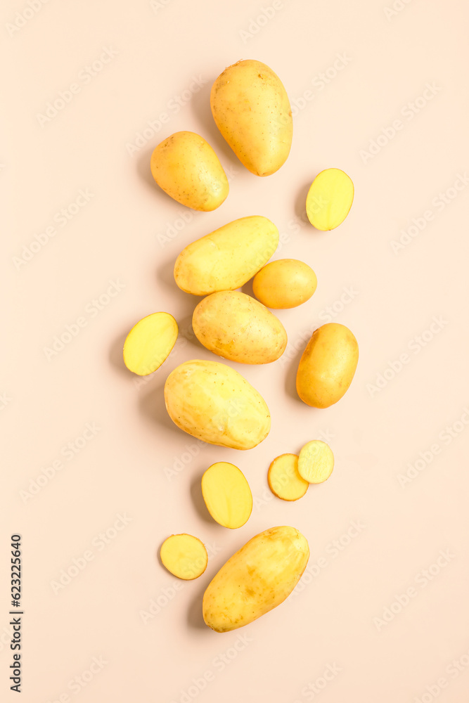 Cut and whole raw potatoes on pink background