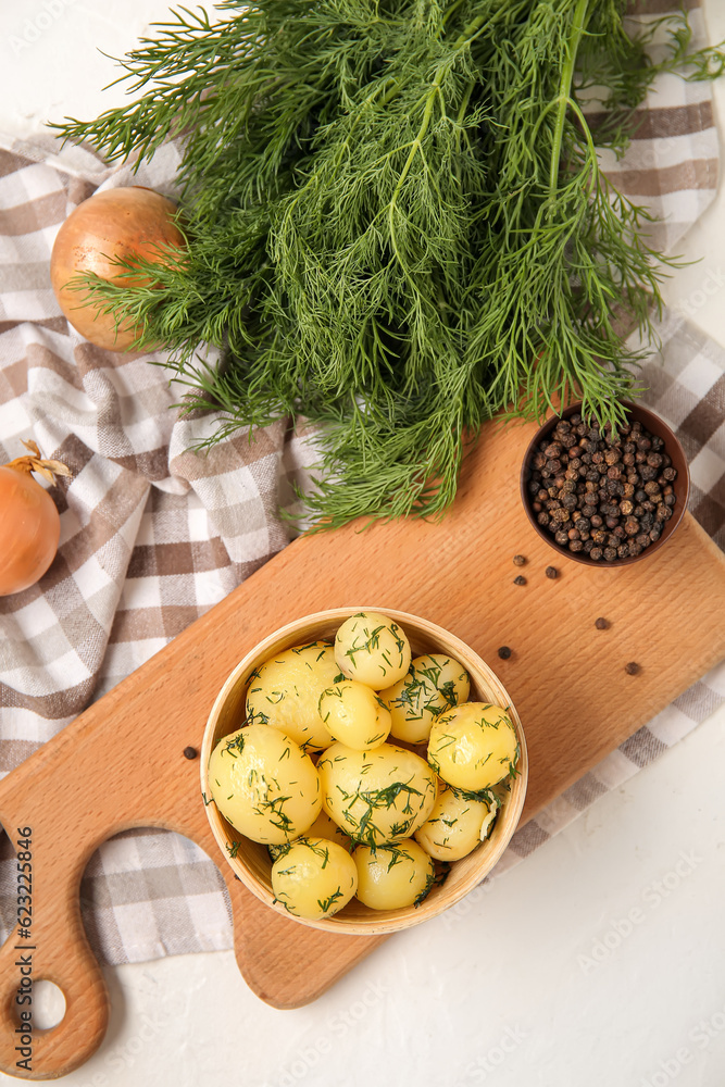 Bowl with boiled baby potatoes on light background