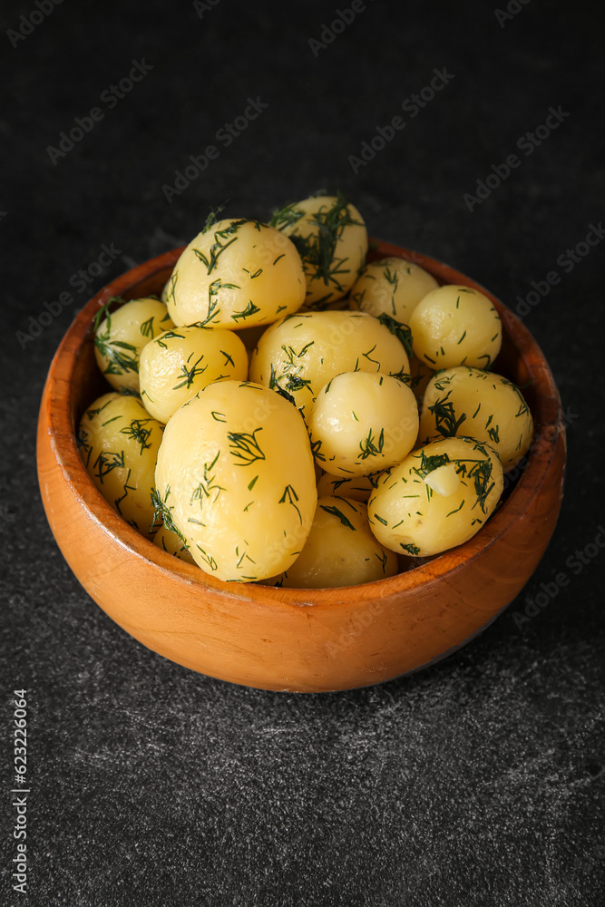 Bowl with boiled baby potatoes on black background