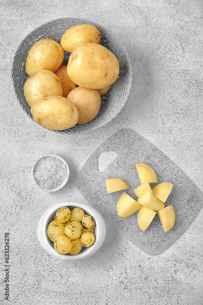 Boiled and raw baby potatoes on light background