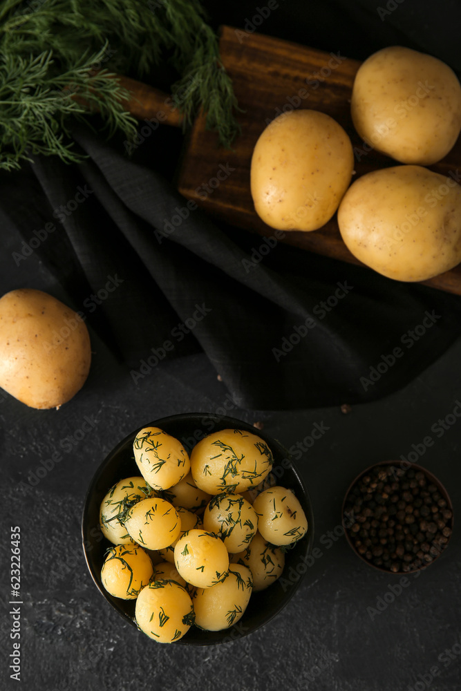 Bowl with boiled baby potatoes on black background