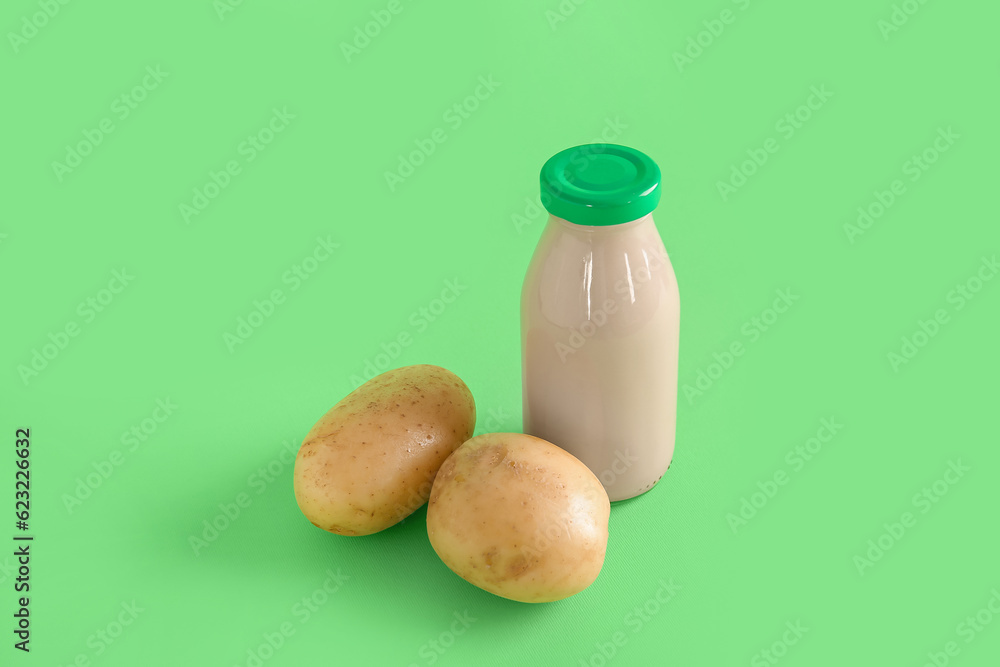 Bottle of tasty potato milk on green background