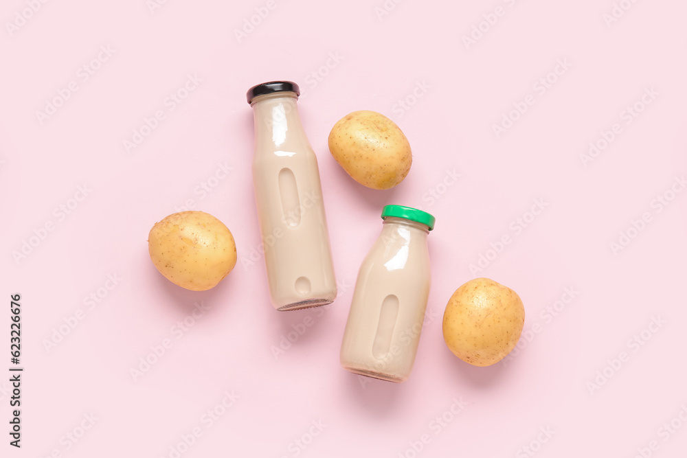 Bottles of tasty potato milk on pink background