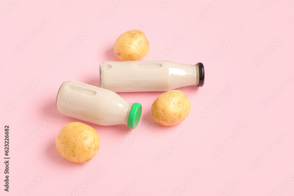 Bottles of tasty potato milk on pink background