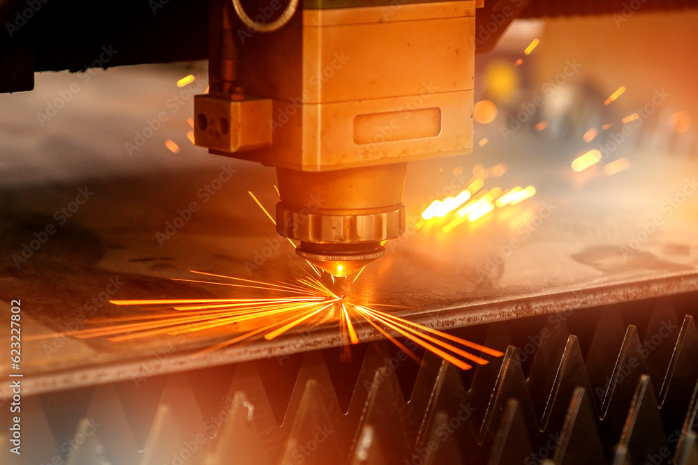 Laser Cutting machine cutting a plate of steel with orange light