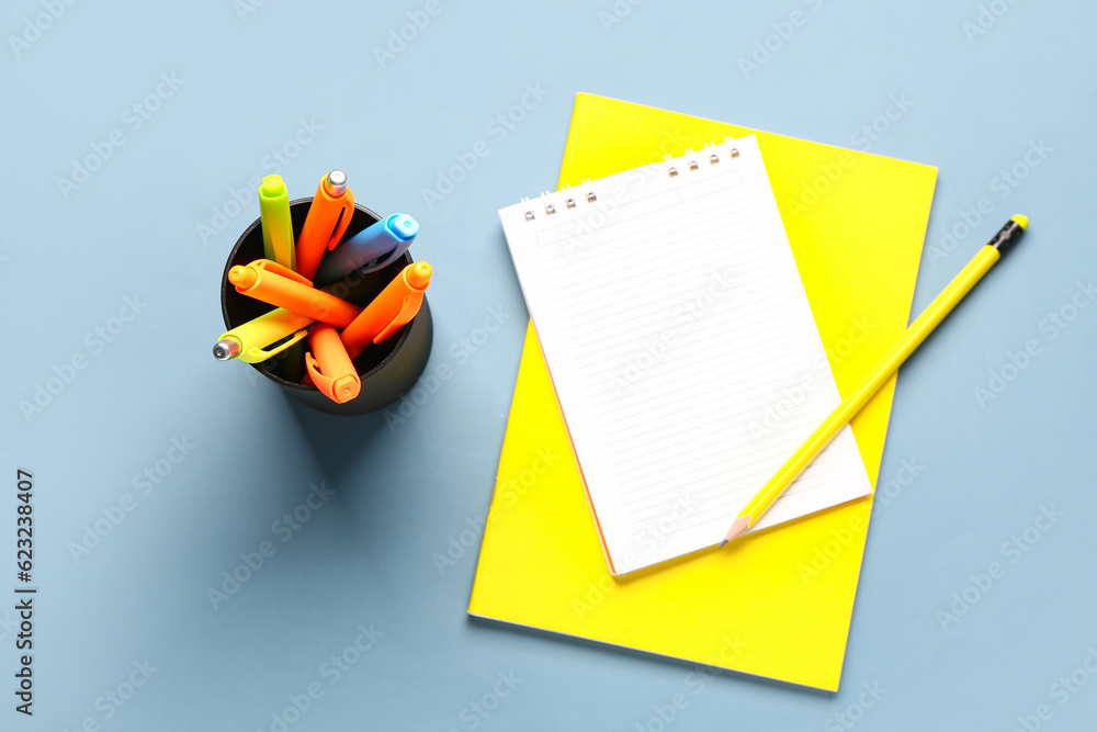 Blank notebook and cup with colorful pens on grey background