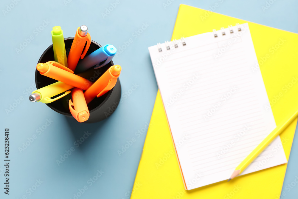 Blank notebook and cup with colorful pens on grey background