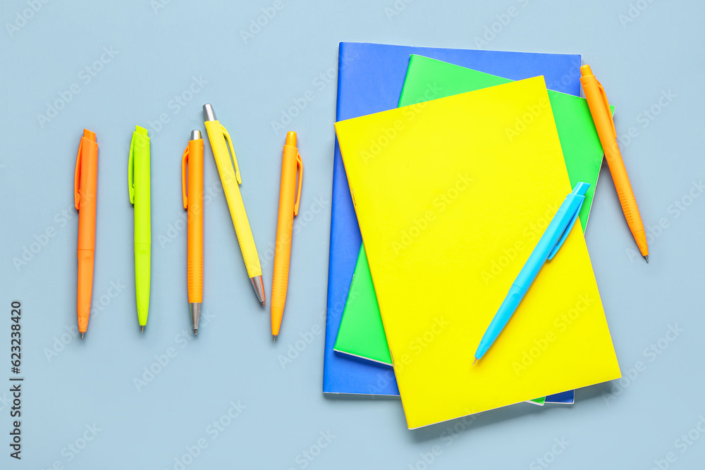 Notebooks with colorful pens on grey background