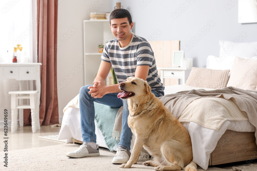 Young man with Labrador dog in bedroom