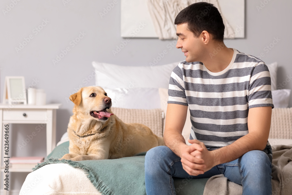 Young man with Labrador dog in bedroom