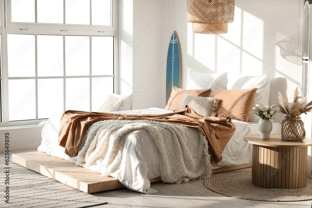 Interior of modern bedroom with surfboard and big bed