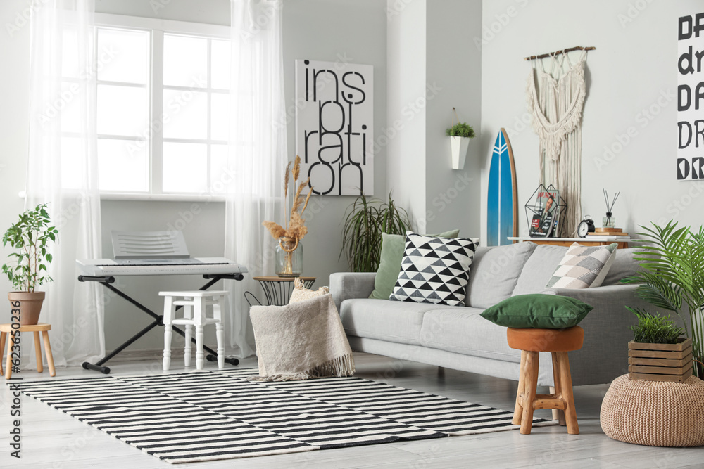 Interior of stylish living room with surfboard, synthesizer and sofa