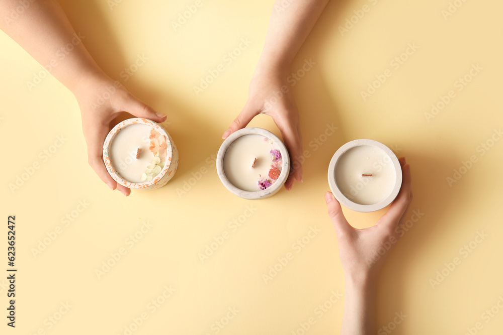 Women holding candles on yellow background