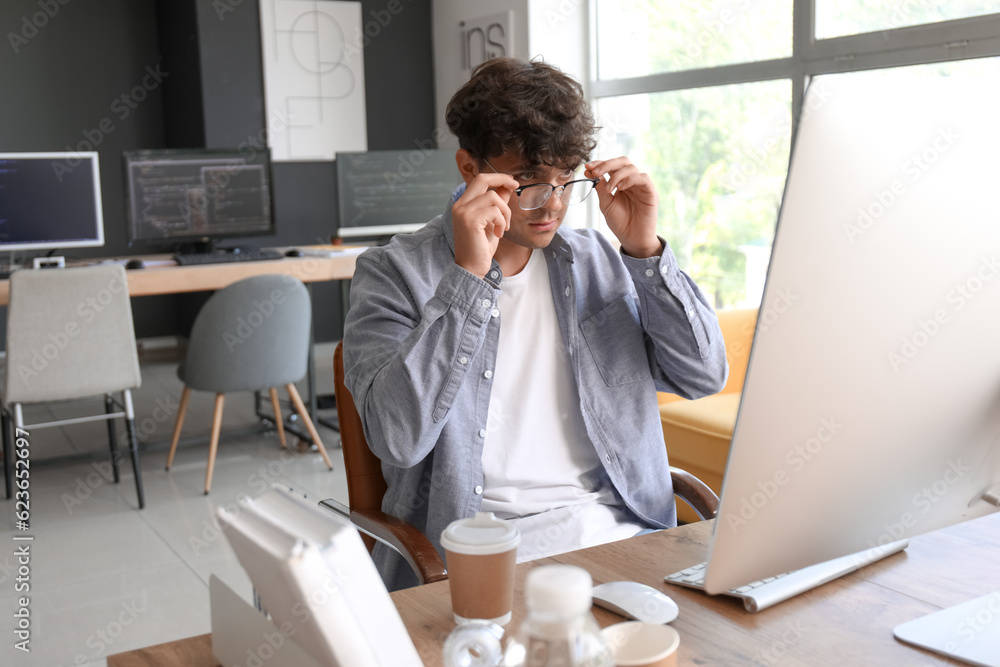 Male programmer with eyeglasses working at table in office