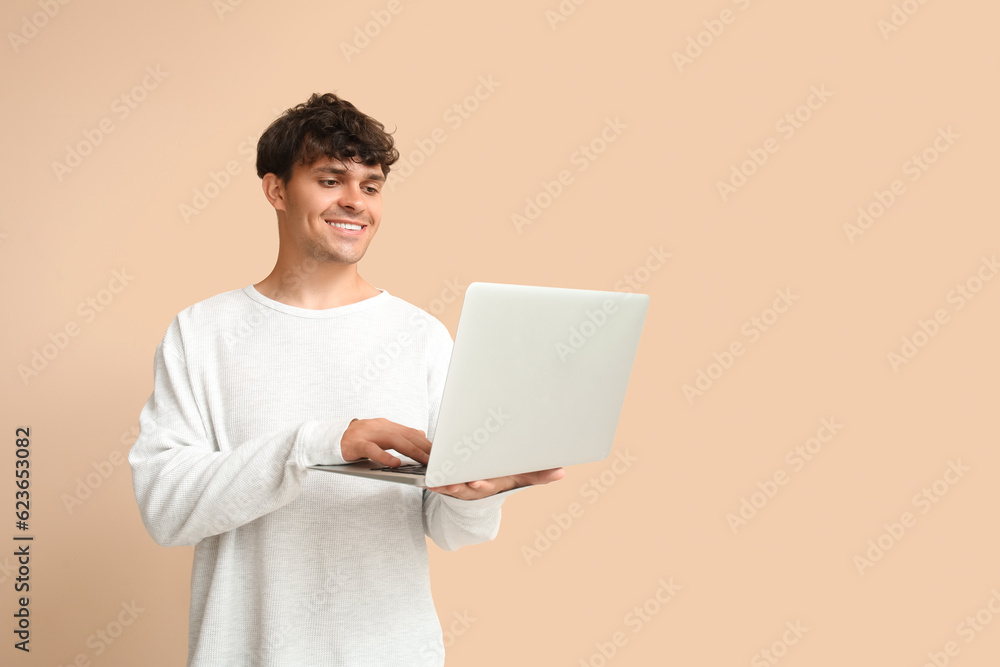 Male programmer working with laptop on beige background