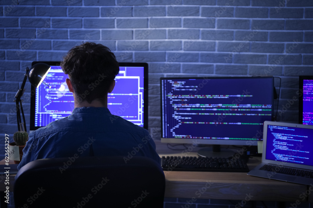 Male programmer working with computer in office at night