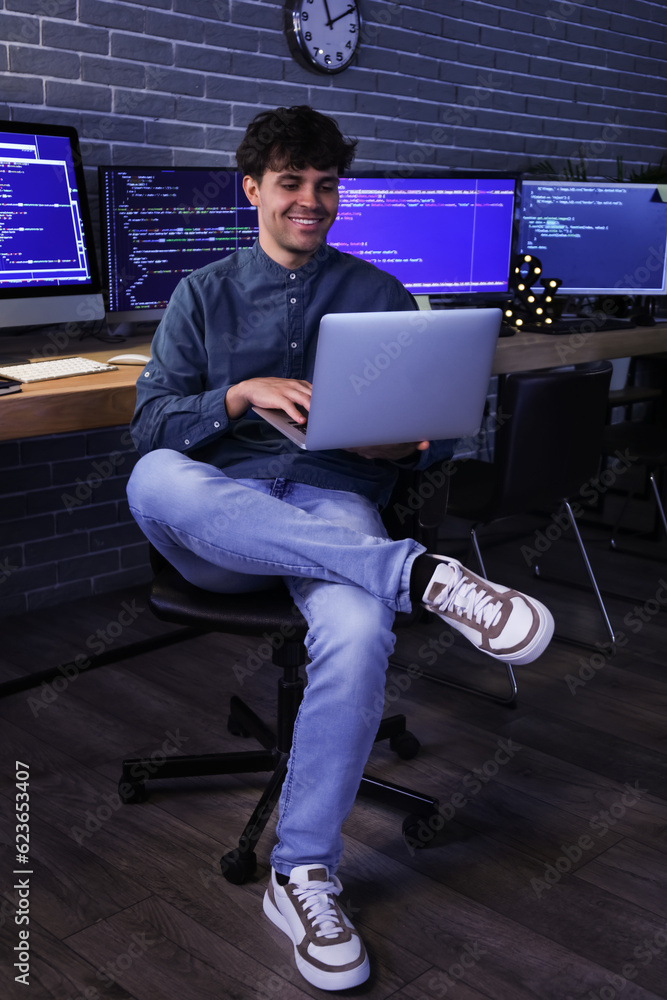 Male programmer working with laptop in office at night