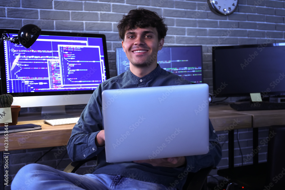 Male programmer working with laptop in office at night