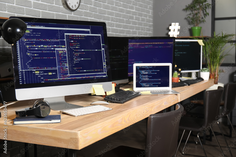 Programmers workplaces with computer monitors in office