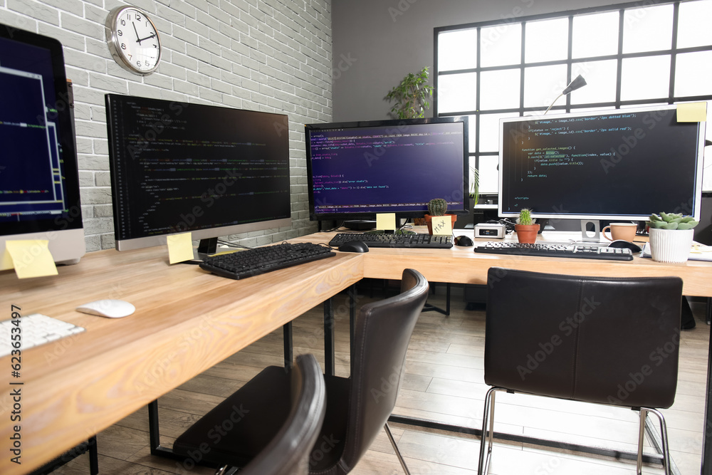 Programmers workplaces with computer monitors in office