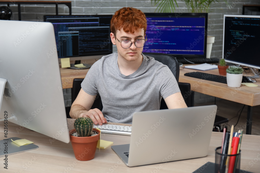 Male programmer working with laptop at table in office