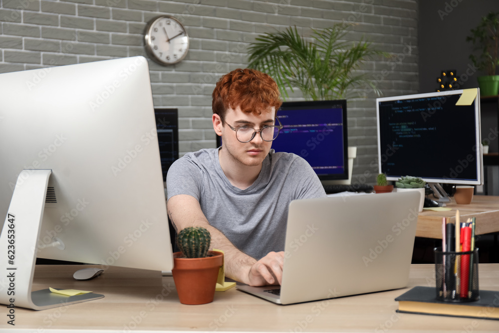 Male programmer working with laptop at table in office